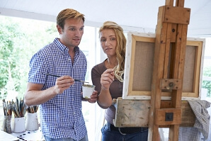 Man och kvinna framför en målarduk
